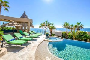 a pool with lounge chairs and the ocean in the background at Villa Alegria in El Pueblito