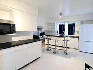 a kitchen with white cabinets and black counter tops at Comfy Stylish Room in the Heart of Vancouver- Private Parking, Self Check-in & just 4 mins to Metrotown! in Vancouver