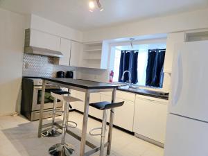 a kitchen with a black counter and stools in it at Comfy Stylish Room in the Heart of Vancouver- Private Parking, Self Check-in & just 4 mins to Metrotown! in Vancouver +13 photos