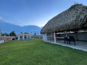 una cabaña con techo de hierba y patio en Villa Encanto Costero, en Monte Gordo