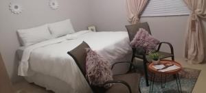 a bedroom with a bed and a table and a chair at Real Touch Spa Accomodation in Mthatha +20 photos