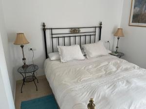 a bedroom with a bed with white sheets and two lamps at Casa Cas in Jerez de la Frontera