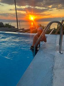 a man in a plunge pool with the sunset in the background at CHRIS SOPO in Ohrid