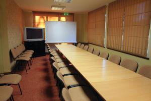 una sala de conferencias con mesas y sillas largas y una pizarra en Grafo Zubovo Hotel & SPA en Bubiai