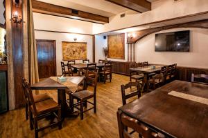 a restaurant with wooden tables and chairs and a flat screen tv at Hotel Curtea Veche in Curtea de Argeş
