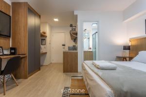 a bedroom with a bed and a desk and a kitchen at Stúdio na Liberdade 270m do metrô MOL0502 in Sao Paulo