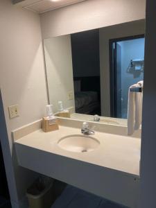 a bathroom with a sink and a large mirror at Economy Suites - Tulsa Airport in Tulsa