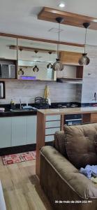 ein Wohnzimmer mit Couch und Küche in der Unterkunft Luxuoso AP no Martim Praia Clube - Martim de Sá in Caraguatatuba