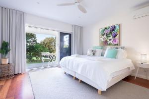 a white bedroom with a bed and a large window at Werri Big Beach House in Gerringong