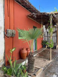 a red building with a palm tree in front of it at Chalé dos Ventos Preá - CE in Cruz
