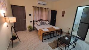 a bedroom with a bed and a table in a room at Nosso Amor Stay in Siolim