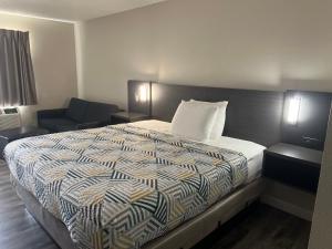 a hotel room with a bed and a chair at Economy Suites - Tulsa Airport in Tulsa