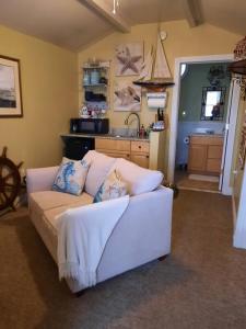 a living room with a white couch and a kitchen at The Highland Cottage on Sheepscot in Edgecomb