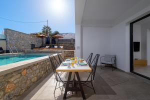 a table and chairs on a patio with a swimming pool at Villa Lambis Athena in Líndos