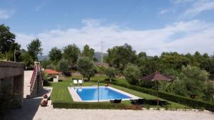 un patio trasero con piscina y sombrilla en Quinta do Correia, en Cabeceiras de Basto