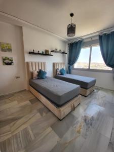 Mont Blanc :Appartement, vue sur mer à 2 minutes de la gare. في طنجة: غرفة نوم بها سريرين ونافذة كبيرة