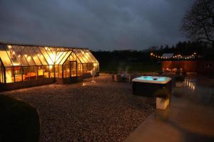 a large greenhouse with a table in front of it at night at Heidebloem max. 12 personen in Lievelde