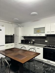 a kitchen with white cabinets and a wooden table at Black Sea Apartment in Constanţa