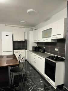 a kitchen with white cabinets and a table and a stove at Black Sea Apartment in Constanţa +5 photos