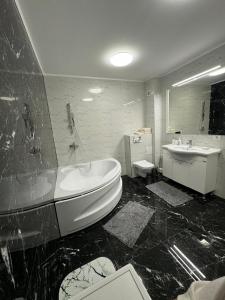 a black and white bathroom with a tub and a sink at Black Sea Apartment in Constanţa