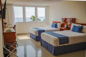 two beds in a hotel room with a view of the ocean at Hotel Hostal de Cortés in Veracruz
