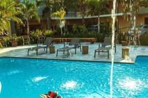 a swimming pool with chairs and a fountain at Hotel Roda D'Agua in Andradina