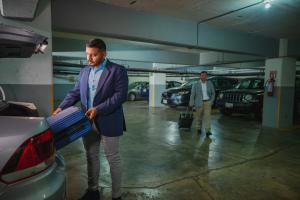 a man is standing next to a car in a parking garage at Hotel Hostal de Cortés in Veracruz