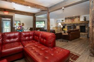 a living room with a red leather couch and a fireplace at Grey Bonnet Inn in Killington