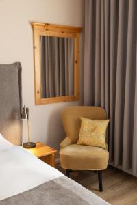 ein Schlafzimmer mit einem Stuhl und einem Spiegel in der Unterkunft Aminess Kadoor Hotel in Karlovac