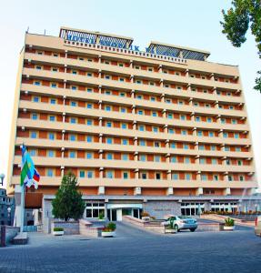 un grand bâtiment avec une voiture garée devant lui dans l'établissement Shodlik Palace, à Tachkent