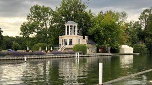 a white house with a tower in the middle of a body of water at 2 bed Serviced Apartment in Henley in Henley on Thames