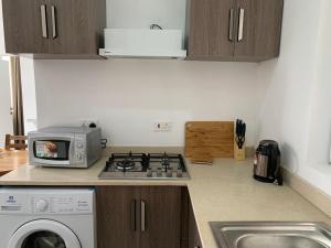 a kitchen with a stove top oven and a microwave at American Mall apartment, Osu in Accra