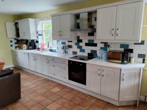 a kitchen with white cabinets and a tile wall at Long Acre, Holiday rental in Central Manorhamilton, Leitrim in Leitrim