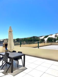 a table and chairs and an umbrella on a patio at Apartamento familiar Praia Barra in Praia da Barra