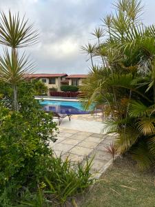 ein Swimmingpool mit Palmen vor einem Haus in der Unterkunft Flat - Condomínio Brisa da Serra - Gravatá in Gravatá