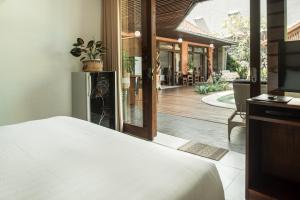 a bedroom with a bed and a view of a patio at Segara Beach House Villa - Kuta in Kuta +66 photos