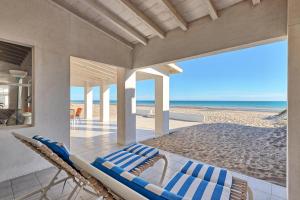 a room with a bed and chairs on the beach at La Perla in Playa Encanto