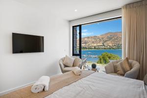ein Schlafzimmer mit einem großen Bett und einem großen Fenster in der Unterkunft Lakeside Luxury in Wanaka