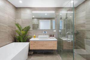 ein Badezimmer mit Badewanne, Waschbecken und Dusche in der Unterkunft Lakeside Luxury in Wanaka + 27 Fotos