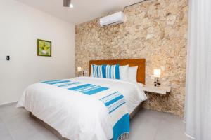 a bedroom with a bed and a stone wall at Casa Itzae Hotel Boutique in Mérida +68 photos
