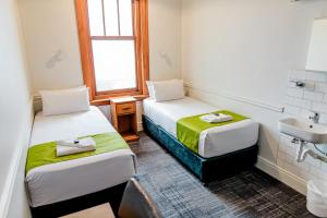 a small room with two beds and a sink at The Cambridge Hotel & Backpackers in Wellington
