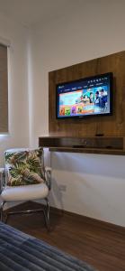 a room with a chair and a tv on a wall at Apartamento Confortável Inteligente in Poços de Caldas