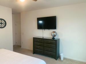 a bedroom with a dresser with a flat screen tv on the wall at Magic Kingdom Villa - Private Master Bedrooms in Kissimmee