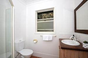 a bathroom with a toilet and a sink and a window at Queen Street Cottage - By Berry Getaways in Berry +8 photos
