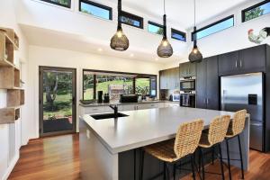 a kitchen with a large white island with bar chairs at Allure - By Berry Getaways in Berry