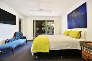 a bedroom with a large bed and a blue chair at Allure - By Berry Getaways in Berry