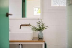 a bathroom with a sink and a vase of flowers on a counter at Fremily Cottage - By Berry Getaways in Berry +3 photos