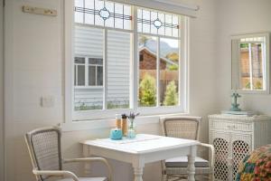 a white table and chairs in a room with windows at Fremily Cottage - By Berry Getaways in Berry