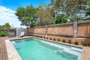 a swimming pool in a backyard with a brick wall at Fremily Cottage - By Berry Getaways in Berry