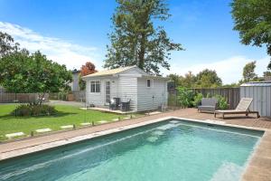 a tiny house with a pool and a backyard at Fremily Cottage - By Berry Getaways in Berry